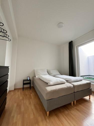 a white bedroom with a bed and a window at urbanstays Linz Denkstraße in Linz