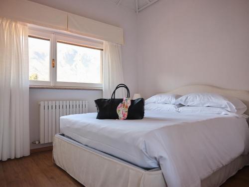a white bed with a purse sitting on top of it at APPARTAMENTO CHRISTINA in Baveno