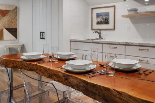 une cuisine avec une table en bois, des assiettes et des verres dans l'établissement Newly Remodeled Bight & Cozy Basement Apartment, à Camas