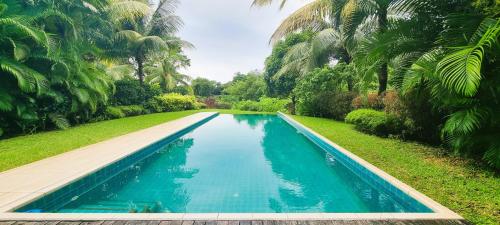 a swimming pool in a yard with palm trees at Modern Villa with Private Pool at Anahita Golf Resort in Beau Champ