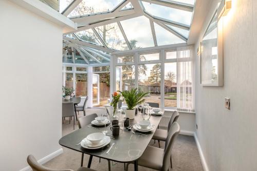 a dining room with a table and chairs and windows at Robinswood House in Gloucester