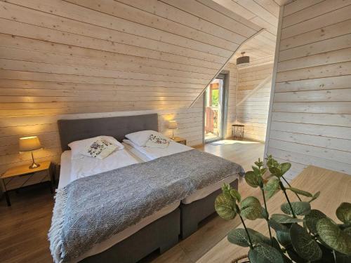 una camera con un letto su una parete in legno di MILOCHÓWKA - dom drewniany bliźniak a Wdzydze Tucholskie