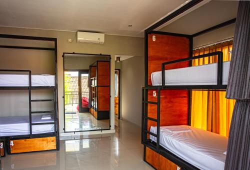 a room with three bunk beds and a mirror at What The Duck Backpackers in Canggu
