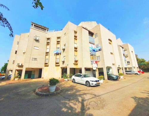 a white car parked in front of a large building at Spacious 3BD Penthouse with Rooftop & Parking in Ra‘ananna