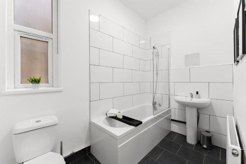 een witte badkamer met een wastafel, een bad en een toilet bij Spacious and Stylish House - Sleeps 12 in Sheffield