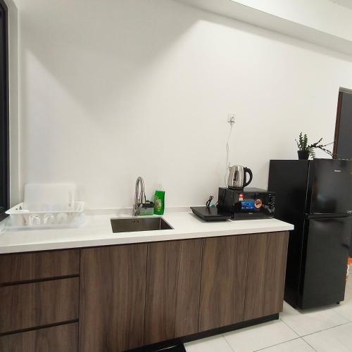a kitchen with a sink and a black refrigerator at New Urban Suite Majestics 3BR Homestay at Georgetown BY URBAN STAYCATION HENG LOD in Jelutong