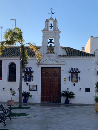 a white church with a large door and a bell tower at La Casa de Albahr in Chipiona