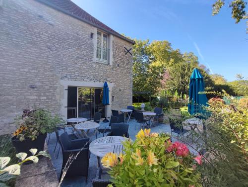 un patio avec des tables, des chaises et des parasols dans l'établissement La Dominotte, à Demigny