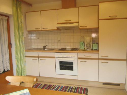 a kitchen with white cabinets and a stove top oven at Ferienwohnung Sporer in Hippach