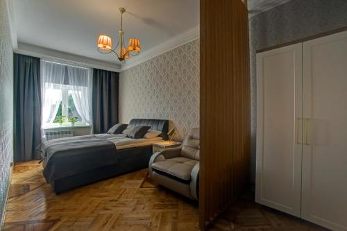 a bedroom with a bed and a chair and a window at APARTAMENTY in Przemyśl