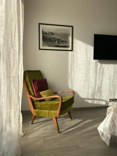 une chaise verte assise dans une pièce avec fenêtre dans l'établissement 1,2,3 soleil, à Porticcio