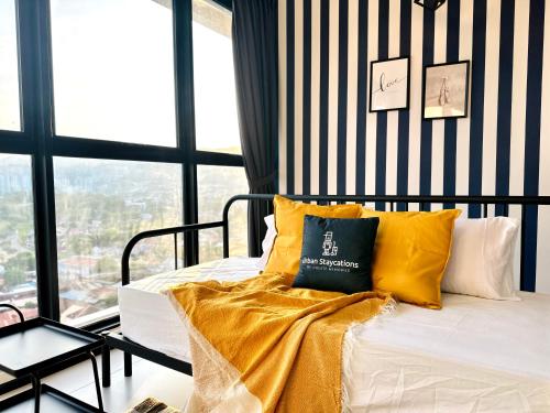 a bed with yellow pillows in a room with windows at New Urban Suite Majestics 3BR Homestay at Georgetown BY URBAN STAYCATION HENG LOD in Jelutong