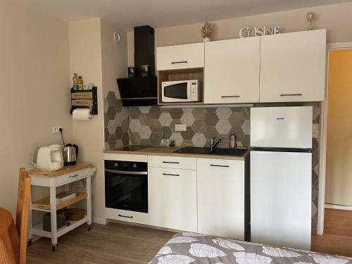 a kitchen with white cabinets and a white refrigerator at Studio meublé 26m² refait à neuf in Bagnoles de l'Orne
