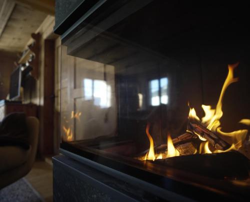 a fireplace with flames in a living room at Historisches Walserhaus near Arosa in Peist