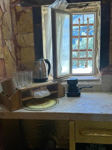 a table with a coffee maker and a window at DanaBlack iris house in Dana