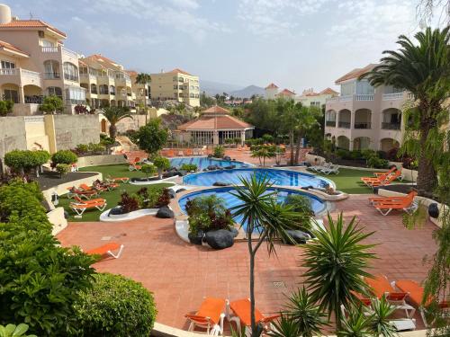 ośrodek z basenem, krzesłami i budynkami w obiekcie GOLF PARK Resort w San Miguel de Abona