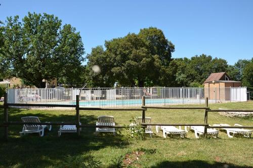 un groupe de bancs devant une clôture avec piscine dans l'établissement Camping Le Roc, à Rocamadour