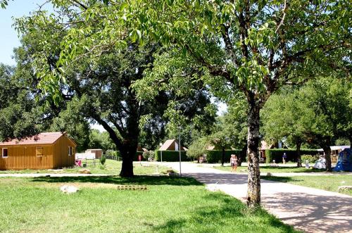 un groupe d'arbres dans un parc avec un bâtiment dans l'établissement Camping Le Roc, à Rocamadour
