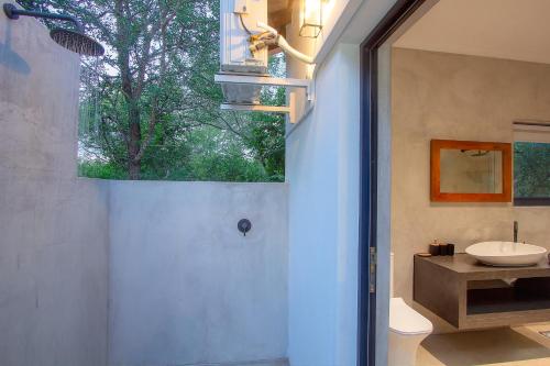 La salle de bains est pourvue d'un lavabo, de toilettes et d'une fenêtre. dans l'établissement Maroela Safari House, à Marloth Park