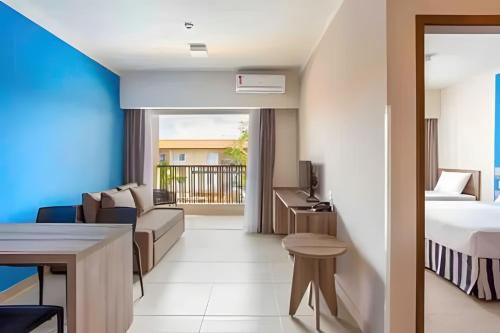 a hotel room with a bed and a living room at Ondas Praia Resort em Porto Seguro in Porto Seguro