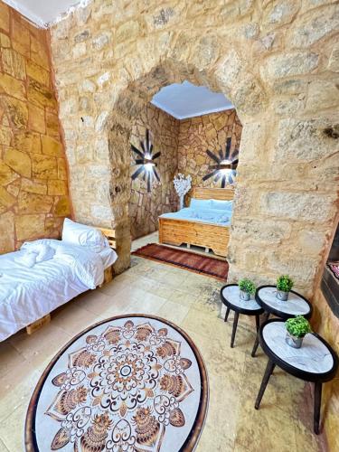 1 dormitorio con pared de piedra, cama y mesas en DanaBlack iris house, en Dana