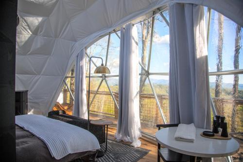 1 dormitorio con cama y ventana grande en Tranquility Luxe Dome - Hot Tub & Luxury Amenities en Swiss