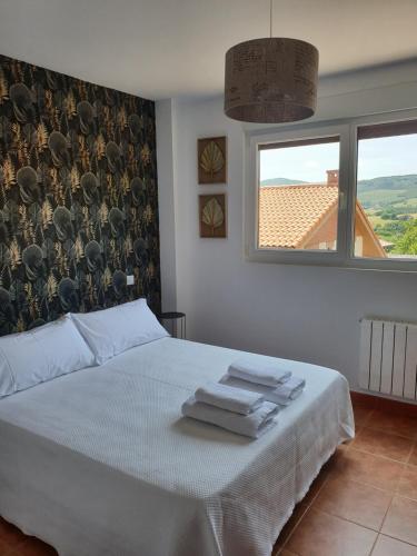 a bedroom with a white bed with towels on it at Casa vacacional Mirador de San Vicente in Serdio