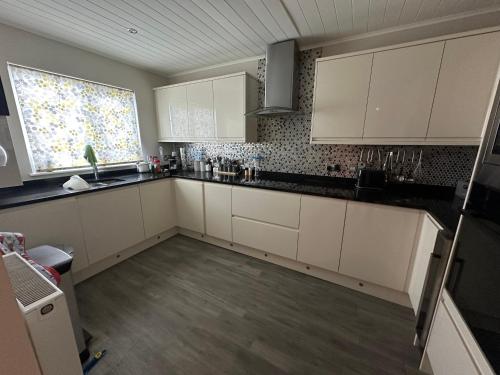 an empty kitchen with white cabinets and a window at Windrush new house in South Cerney