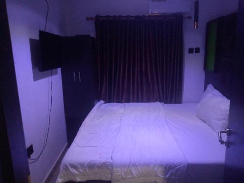 um quarto com uma cama com lençóis brancos e uma janela em light house hotel lekki phase 1 em Lekki