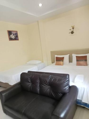 a black leather couch in a room with two beds at Wattana Bungalow in Nai Yang Beach