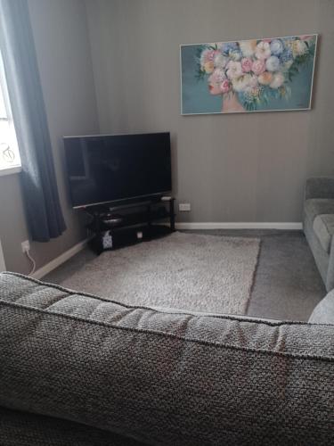 a living room with a couch and a flat screen tv at Riverside in Musselburgh