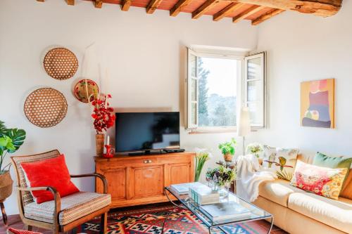 a living room with a couch and a tv at Casa Noscali al Borghetto in Collodi