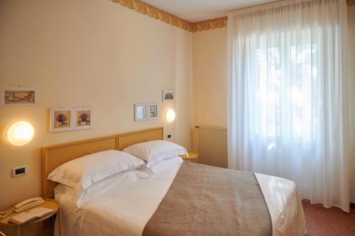 a bedroom with a bed and a window with a phone at Villa Arizona in Milano Marittima