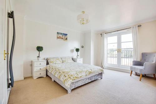 a bedroom with a bed and a chair and a window at Modern 5 Bedroom House with Free Parking. Only 30 mins to Bond Street in Stanmore