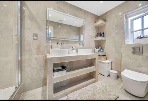 a bathroom with two sinks and a shower and a toilet at Modern 5 Bedroom House with Free Parking. Only 30 mins to Bond Street in Stanmore