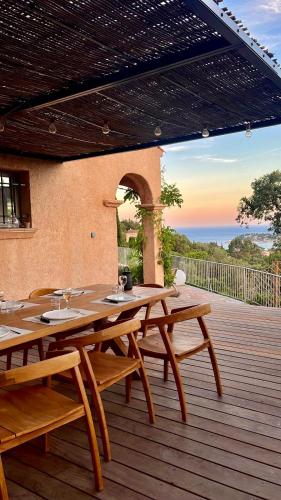 une table et des chaises en bois sur une terrasse en bois dans l'établissement Villa les santons vue panoramique mer Golfe de Saint Tropez 4 étoiles, à Cavalaire-sur-Mer