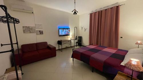 a bedroom with a bed and a couch and a tv at La Contessa B&B Torrette in Mercogliano