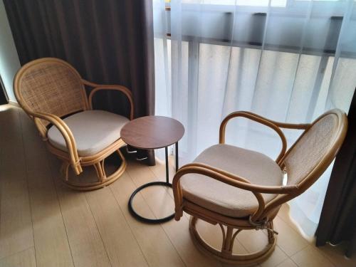 two chairs and a table in front of a window at Guesthouse Sakichi in Beppu