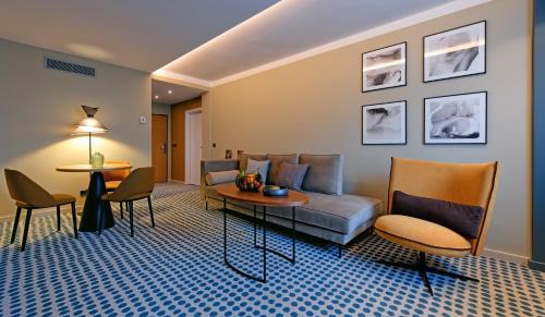 a living room with a couch and a table and chairs at Novotel Luxembourg Kirchberg in Luxembourg