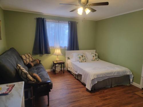 a bedroom with a bed and a couch and a ceiling fan at Josephine's Bed & Breakfast in Titusville