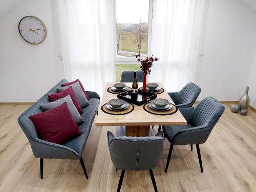 sala de estar con mesa, sillas y reloj en Premium Vulkaneifel Chalet, en Lutzerath