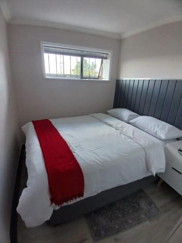 a bedroom with a bed with a red and white blanket at Muhlemoholo Guest House in Maseru