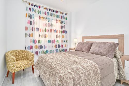 1 dormitorio con 1 cama, 1 silla y 1 cortina en Bonito Apartamento Costa Tropical, en Polopos