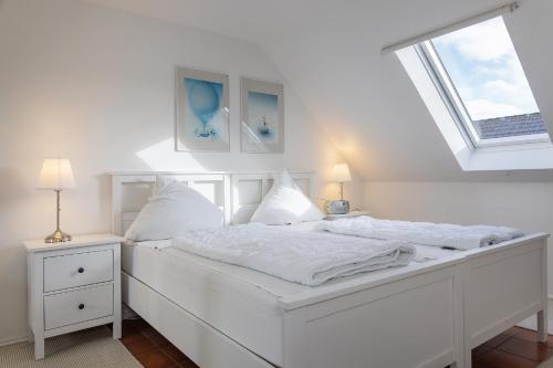 a white bedroom with a white bed and two night stands at Haus Harle 50205 Ferienwohnung Harle 4 in Harlesiel