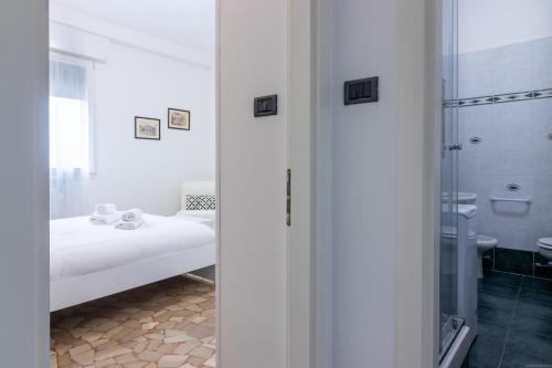 Jest to biały pokój z łóżkiem i łazienką. w obiekcie HouSmart Galeotti 16 w Bolonii