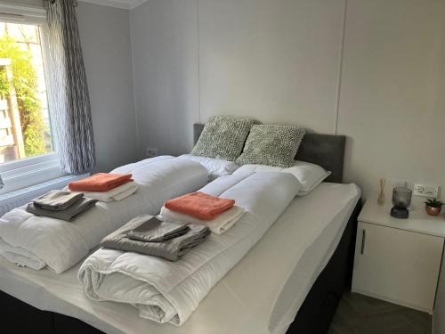 een groot wit bed in een kamer met een raam bij Gloednieuw luxe chalet met infraroodsauna in Hoenderloo