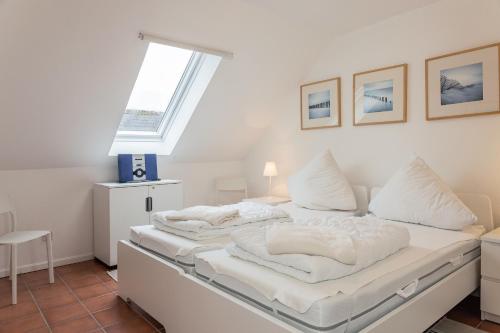 een slaapkamer met 2 witte bedden en een raam bij Haus Harle 50203 Ferienhaus Harle 1 in Harlesiel