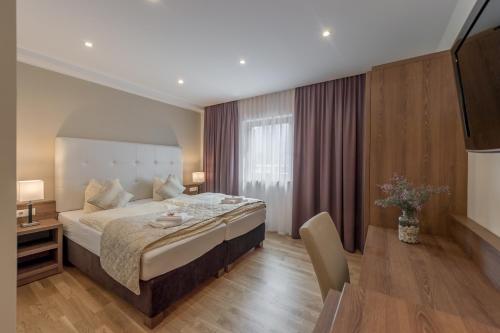 a bedroom with a bed and a desk and a television at Gasthof Ambachhof in Oetz
