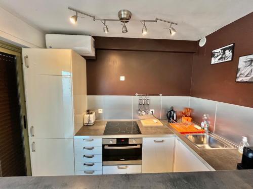 a kitchen with white cabinets and a stove and a sink at La Pépinière in Cannes