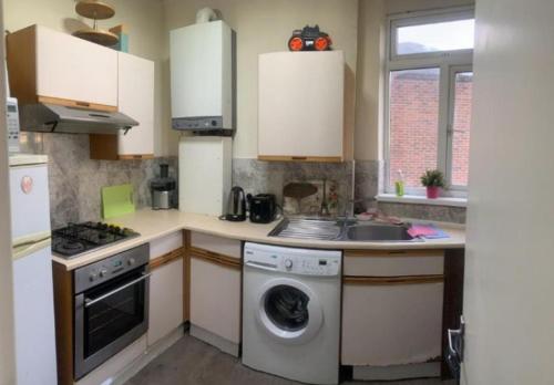 a kitchen with a washing machine and a dishwasher at Room in Kilburn in London